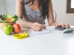 Woman calculating calories in her meal and taking note. 1 Woman calculating calories in her meal and taking note. 1